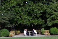 Barack Obama seating at a table in a garden, drinking a beer with Joe Biden, Henry Louis Gates Jr. and James Crowley