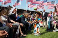 Barack Obama, with Michelle Obama, greeting a young boy dressed in traditional outfits.