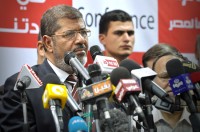 Mohamed Morsi facing multiple microphone during press conference.