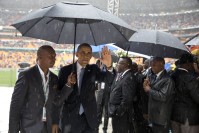 Barack Obama leaving the stadium under the rain, accompanied by a man holding an umbrella.