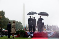 Obama and Le Myung-bak standing next to each other under the rain. Behind them, two soldiers holding umbrellas.