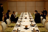 Barack Obama taking a seat at the dinner table in front of Yukio Hatoyama.