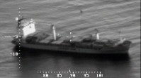 Black and white still frame from video of a boat. On the bottom and the left, latitude and longitude coordinates.