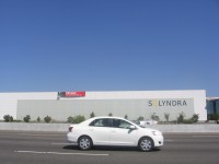A large factory building owned by Solyndra, with a "For Sale" sign on it.