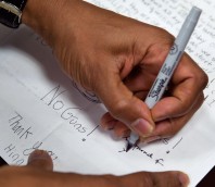 Barack Obama's left hand signs a letter with the writing "No Guns !"