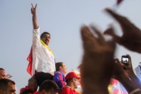 Nicolás Maduro surrounded a crowd, doing the peace sign, the Columbian flag around his neck.