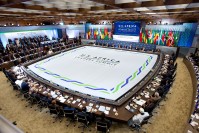 Barack Obama and African leaders seating at a table around a big sign "U.S. Africa Leaders Summit 2014 Washington" In the background, flags of the different African delegation.